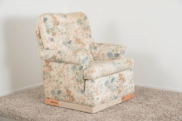 A wooden surround fitted under a floral lounge chair to raise the chair height by around 10 cm.